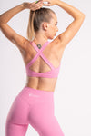 Pink color athletic wear worn by a women in white background along with matching yoga pants