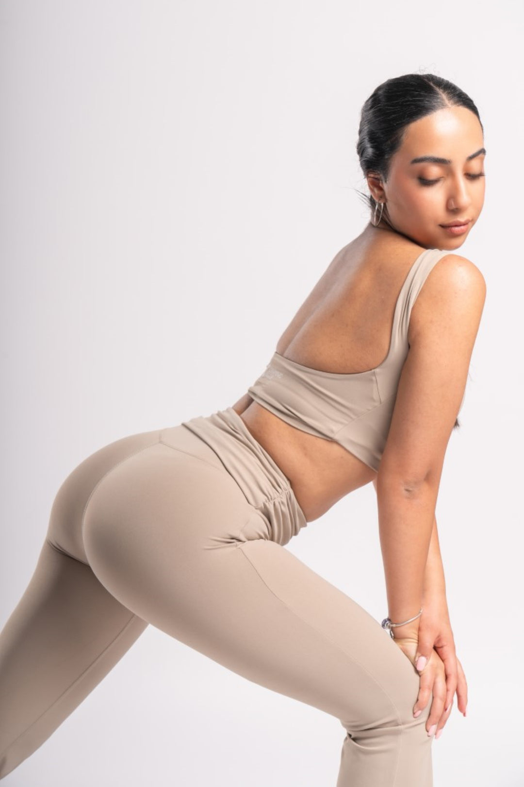 Woman wearing a backless crop top and high-waisted flared yoga pants in a workout pose