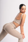 Woman wearing a backless crop top and high-waisted flared yoga pants in a workout pose