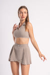 Beige cropped gym top with collars, paired with a pleated skirt for an athletic workout look