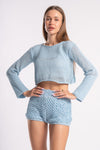 Stylish woman dressed in a light blue mesh two-piece, featuring a cropped top and shorts