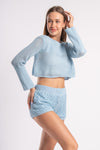 Young woman in a casual blue crochet outfit, posing with a relaxed and happy expression