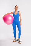 A woman in a blue jumpsuit is holding a pink ball