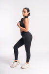 Person in a breathable black sports bra and squat-proof yoga leggings, posing confidently.