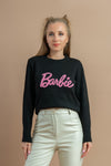 Woman wearing a black sweatshirt with pink Barbie logo