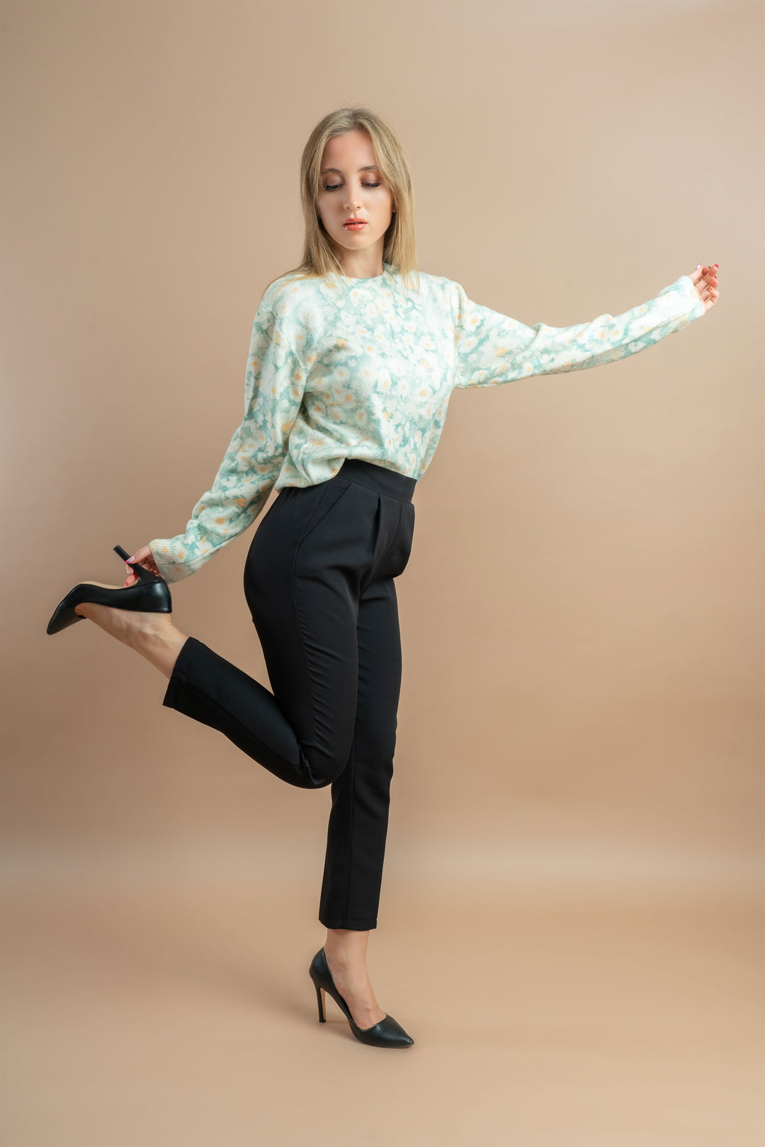 Woman dressed in a floral mint-green sweater and black pants