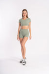 Model wearing green fitness set - crop top and shorts