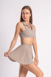 Beige workout set with a collared crop top and skirt, designed for activewear at the gym