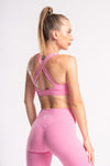 pink color performance gear set of yoga pants and cross back sports bra on a women standing with back pose