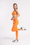 Woman in matching orange sports bra and yoga pants