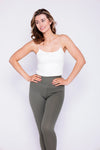 The woman showcases a modern look in a white top and olive green leggings