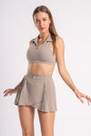 Athletic beige outfit for women, with a cropped collared top and matching pleated skirt.