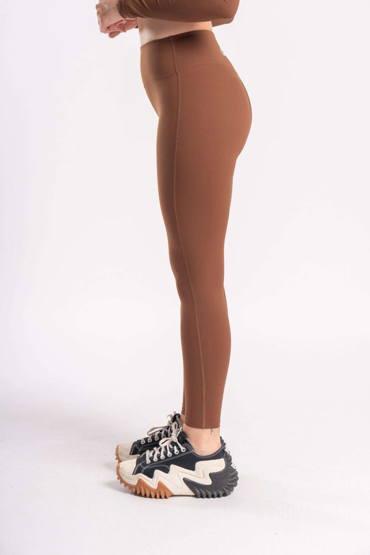 girl wearing a yoga pants of brown color with sports shoes in white background