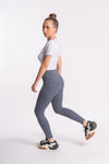 woman styling off white crop top with gray yoga pants and sports shoes for stylish look