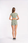 Sporty woman in olive green two-piece fitness set of shorts and crop top