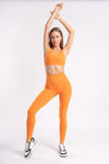 Athlete wearing a vibrant orange sports bra and yoga pants, prepared for a yoga session