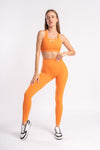 Person in an orange athletic outfit, including a sports bra and leggings