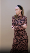 Woman in a knee-length, tiger-print fitted dress, exuding confidence in a neutral studio