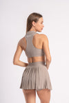 Collared beige crop top and pleated skirt set, designed for women’s gym workouts.