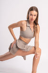 Two-piece workout set in beige, with a sleeveless collared crop top and a pleated skirt