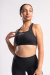 Woman wearing a matching black yoga set, featuring a racerback sports bra and stretchable leggings