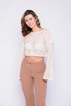 Stylish woman in a cream mesh crop top with flared sleeves, wearing high-waisted brown pants