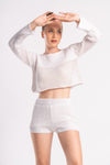 Stylish woman in a white knit set, showcasing design of the crop top and shorts