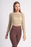 A textured, long-sleeve cropped top with intricate beige and light green patterns