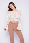 woman styling off white cream mesh sweater paired with brown pants smiling beautifully